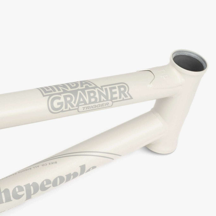 Close-up of WETHEPEOPLE TRIGGER FRAME BMX bike frame in white with Linda Grabner signature graphics