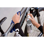 Person applying KRUSH SHINE PROTECTION SPRAY on a bicycle frame with a cloth.