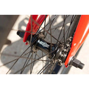 Close-up of the Sunday Primer 20" BMX bike’s black sealed cassette rear hub with red frame fork and black spokes