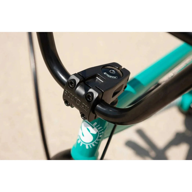 Close-up of Sunday Primer 20" bike black handlebar stem and turquoise frame with Sunday logo