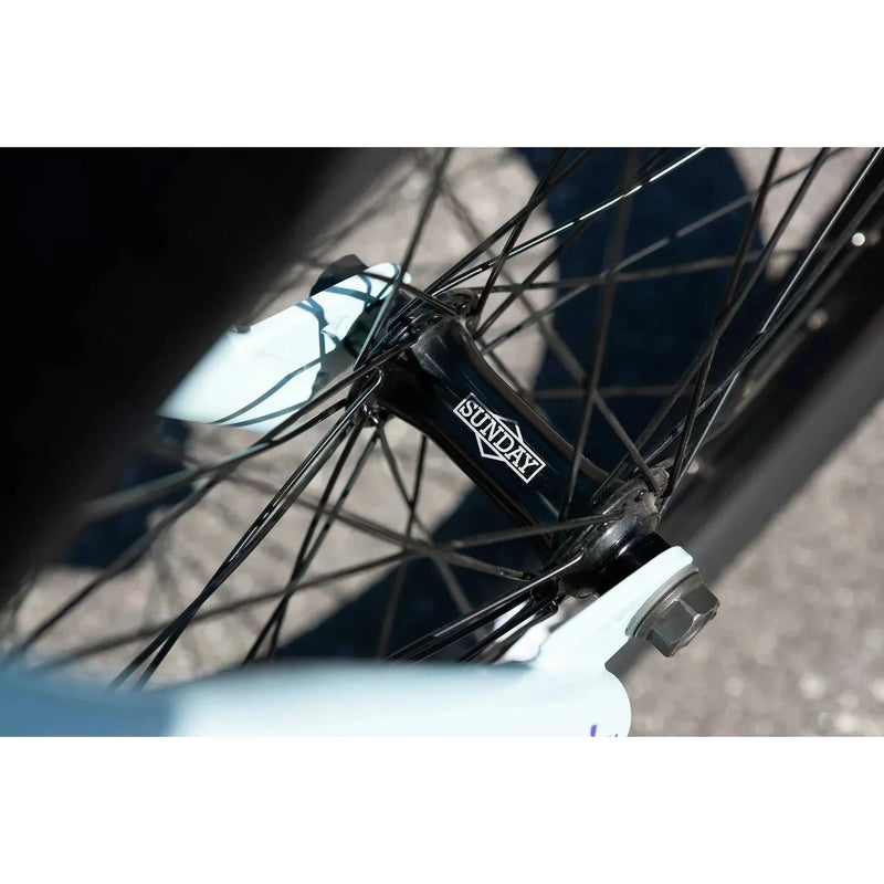 Close-up of black Sunday Forecaster Ross bike hub with spokes and light blue frame detail