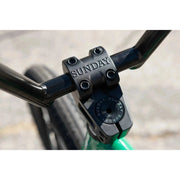 Close-up of the Sunday Forecaster BMX bike's black handlebar stem with "SUNDAY" engraving on a green frame