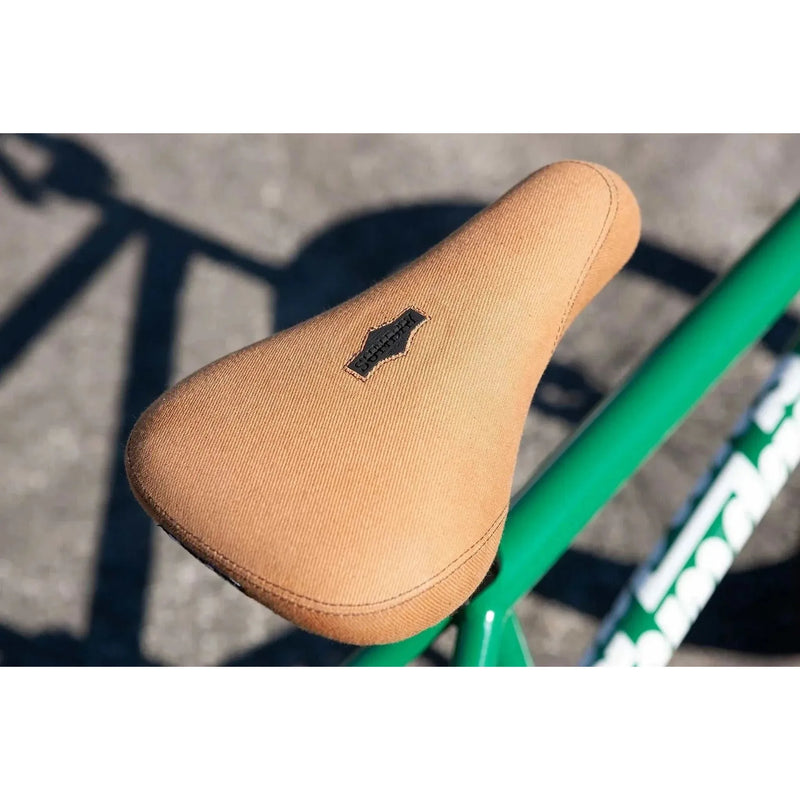 Close-up of tan Sunday Forecaster pivotal seat on green chromoly BMX bike frame