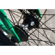 Close-up of the black sealed front hub with spokes on the green frame of the Sunday Forecaster BMX bike.
