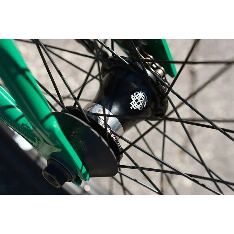 Close-up of the black sealed front hub with spokes on the green frame of the Sunday Forecaster BMX bike.