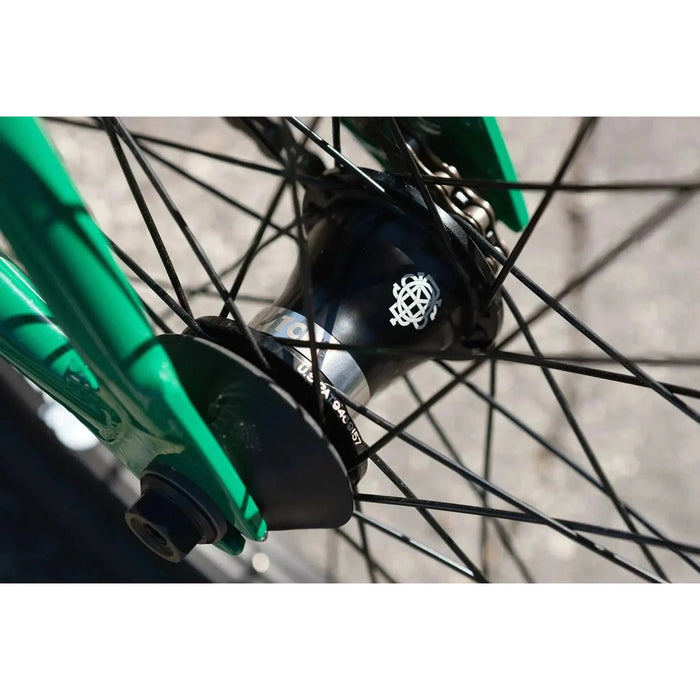 Close-up of the black sealed front hub with spokes on the green frame of the Sunday Forecaster BMX bike.