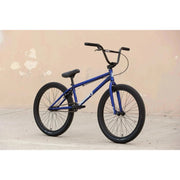 Blue SUNDAY MODEL C 24-inch BMX bike with black tires and handlebars against a beige wall background