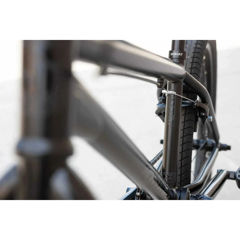 Close-up view of the black Sunday Model C 24" BMX bike frame and rear tire with integrated brake system.
