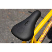 Black BMX saddle with embossed Sunday Bikes logo on matte mustard Sunday EX Arteaga frame