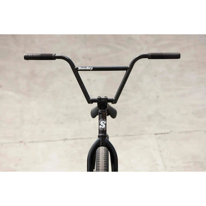 Front view of black Sunday EX Elstran 20" BMX bike with chromoly bars and tires against a concrete background