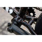 Close-up of the Sunday EX Elstran BMX bike's black chromoly frame with copper paint splatter detailing and crank arm assembly.