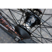 Close-up of SUNDAY EX ELSTRAN bike's black sealed front hub with spokes and copper speckled frame details