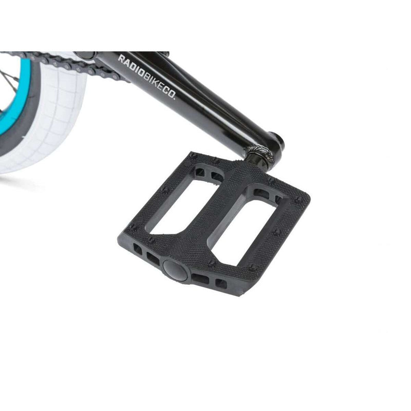 Close-up of black pedal and crank arm on RADIO ASTRON FS COMPLETE BIKE with white and blue tire in background