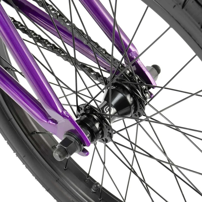 Close-up of the purple RADIO DARKO bike rear wheel hub and spokes with black tire and chain.
