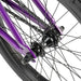 Close-up of the purple RADIO DARKO bike rear wheel hub and spokes with black tire and chain.
