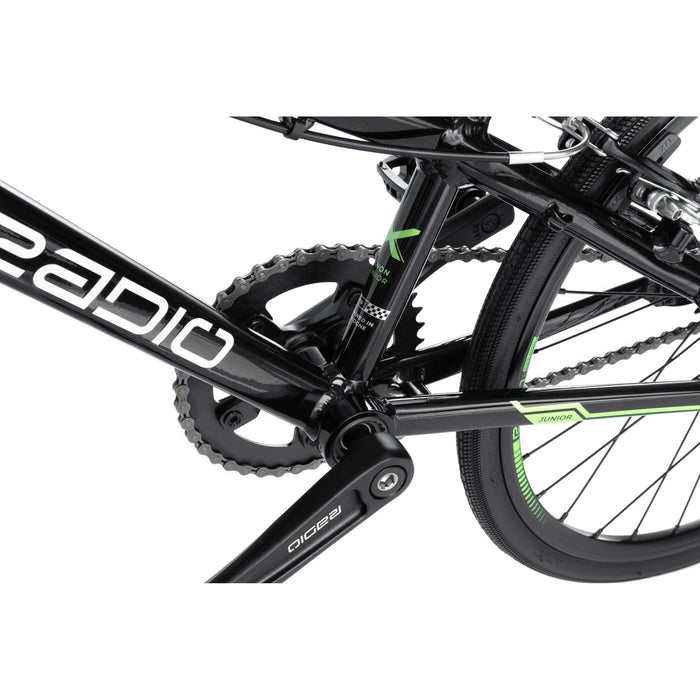 Close-up of RADIO RACELINE XENON JUNIOR black alloy bike crankset, chain, and rear wheel with green accents
