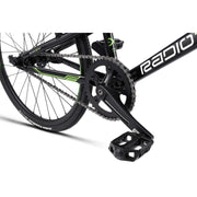 Close-up of RADIO RACELINE XENON JUNIOR bike black crankset, chain, and pedal with 20-inch tire and alloy frame details