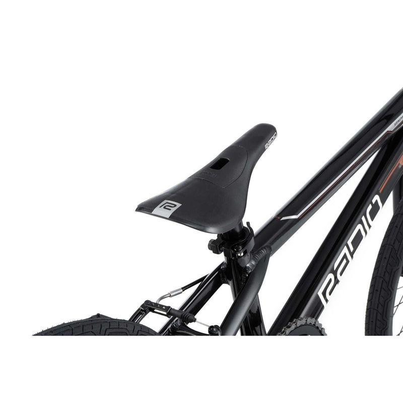 Close-up of Radio Raceline Xenon PRO black bike seat and part of frame with tire visible, highlighting sleek design and branding.