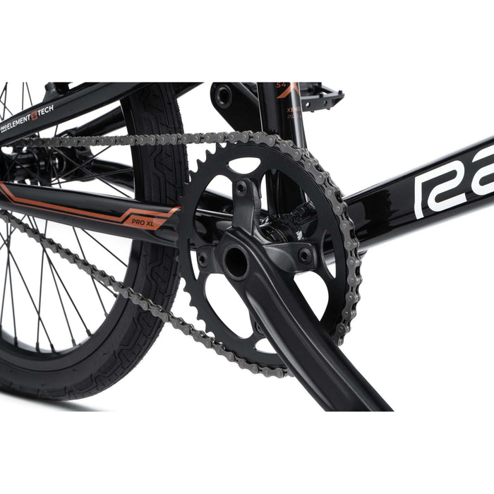 Close-up of Radio Raceline Xenon PRO bike crankset and chain on black frame with orange detailing