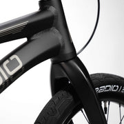 Close-up of RADIO RACELINE QUARTZ PRO black alloy bike frame and carbon fork with detailed welds and tire branding.