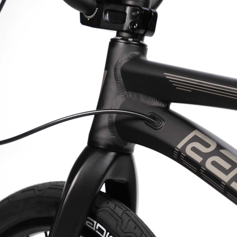 Close-up of the matte black RADIO RACELINE QUARTZ PRO bike frame and front fork with integrated cable routing and tubular tire.