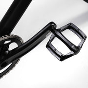 Close-up of a black RADIO RACELINE QUARTZ PRO bike pedal and crankarm with chainring on a white background