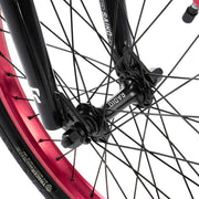 Close-up of RADIO SAIKO 20 bike front wheel hub and black fork with purple rim and spokes detail