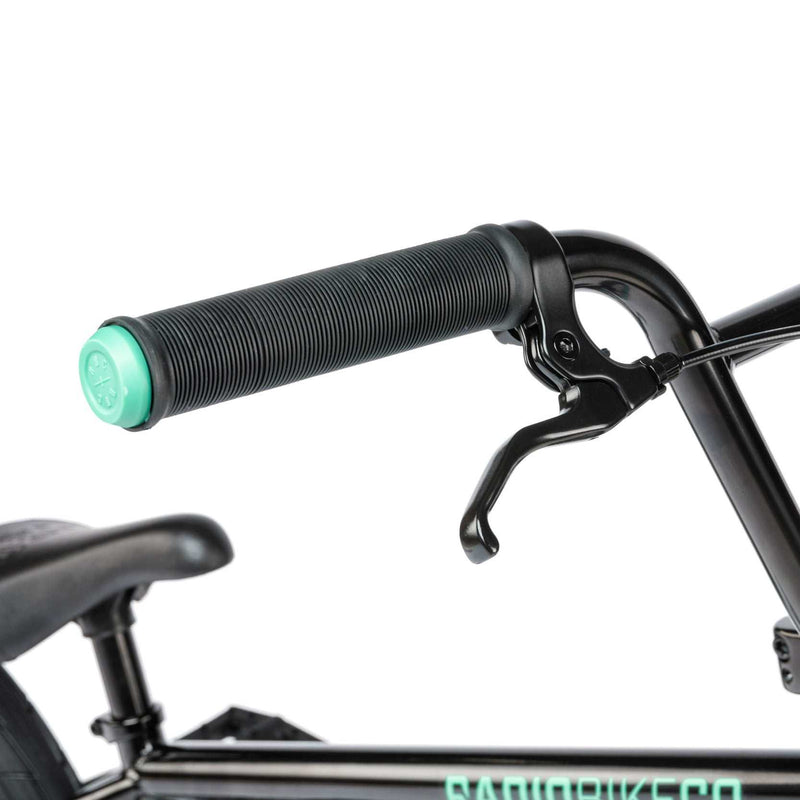 Close-up of RADIO SAIKO 20 bike's black handlebar grip and brake lever with part of the seat and frame visible