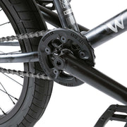 Close-up of Wethepeople Justice Bike black sprocket and chain near rear tire and pedal