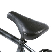 Close-up of black Wethepeople Justice Bike pivotal seat with embossed logo and sleek stitching on black frame seat post