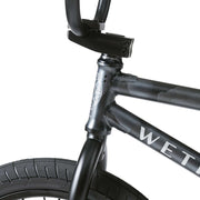 Close-up of Wethepeople Justice Bike black frame and front tire with sealed bearing headset and branded logo on the top tube