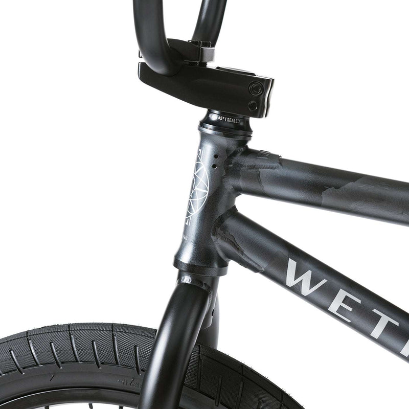 Close-up of Wethepeople Justice Bike black frame and front tire with sealed bearing headset and branded logo on the top tube