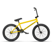 Yellow Wethepeople Justice Bike with black tires and seat, urban BMX design with 20.75" top tube and 22mm offset fork