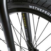Close-up of WETHEPEOPLE JUSTICE BIKE black front fork and wheel with branded tire and spokes details