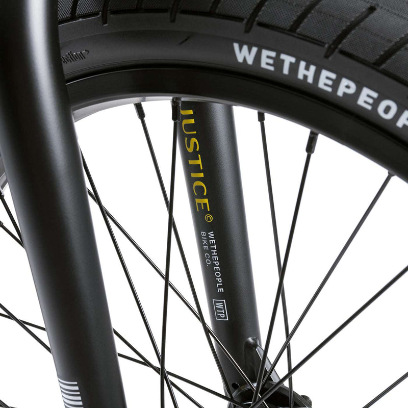 Close-up of WETHEPEOPLE JUSTICE BIKE black front fork and wheel with branded tire and spokes details