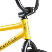 Close-up of the yellow WETHEPEOPLE JUSTICE BIKE frame and black handlebar stem showing branding details