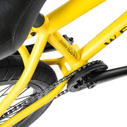 Close-up of yellow Wethepeople Justice Complete Bike frame and chainring with black chain and rear tire
