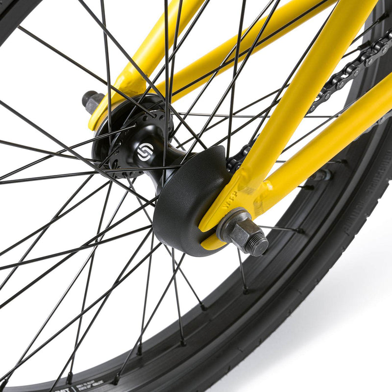 Close-up of the yellow WETHEPEOPLE JUSTICE BIKE rear wheel with black hub, spokes, and plastic hub guard.