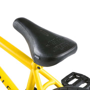 Close-up of black Wethepeople Justice bike seat mounted on yellow frame with black pedal visible