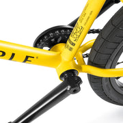 Close-up of yellow Wethepeople Justice Bike frame and black crank arm with chain and rear tire details