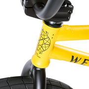Close-up of the yellow Wethepeople Justice Bike frame and front fork with black tire and integrated headset design