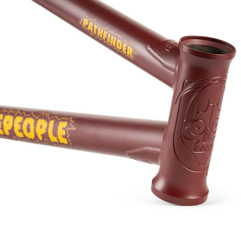 Close-up of maroon WETHEPEOPLE PATHFINDER BMX bike frame with yellow branding and engraved head tube design