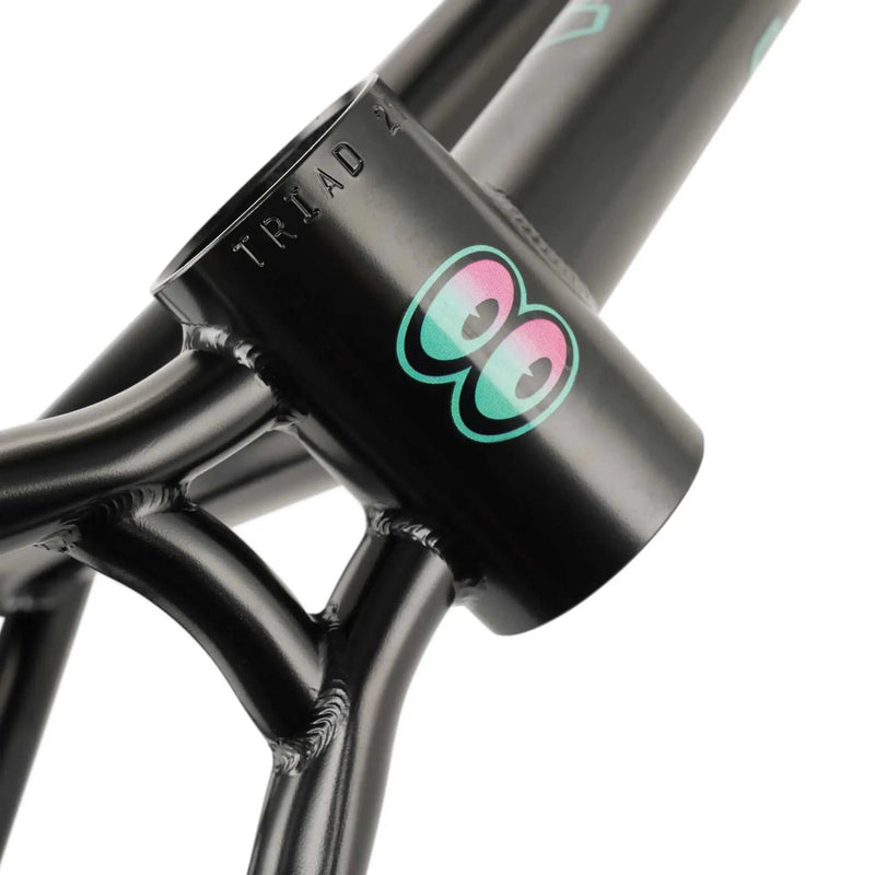 Close-up of WETHEPEOPLE TRIGGER FRAME BMX bike frame in black with turquoise and pink eye logo on the head tube