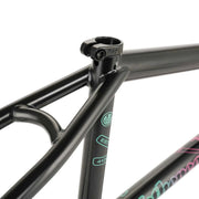Close-up of the black WETHEPEOPLE TRIGGER FRAME BMX bike frame showing the seat clamp and top tube junction with signature decal details.