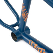 Close-up of WETHEPEOPLE TRIGGER FRAME in matte navy blue with orange branding and smooth welds on BMX bike frame