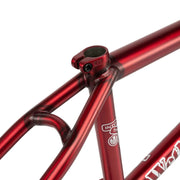 close-up of a red WETHEPEOPLE TRIGGER FRAME BMX bicycle frame with visible welds and seat clamp on a white background