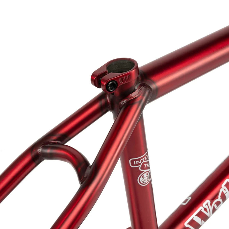 close-up of a red WETHEPEOPLE TRIGGER FRAME BMX bicycle frame with visible welds and seat clamp on a white background