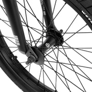 Close-up of the front wheel and fork of the WETHEPEOPLE JUSTICE BIKE showing black spokes, hub, and tire details.