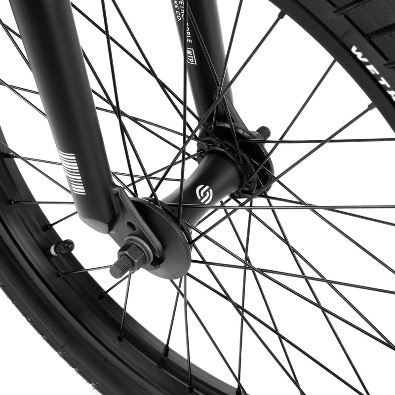 Close-up of the front wheel and fork of the WETHEPEOPLE JUSTICE BIKE showing black spokes, hub, and tire details.