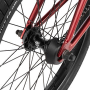 Close-up of rear wheel hub and black hub guard on red Wethepeople Justice bike frame with black tire and spokes